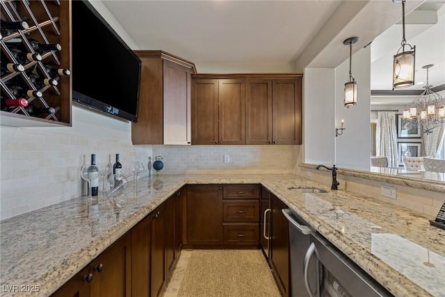 kitchen featuring tasteful backsplash, light stone countertops, sink, and pendant lighting