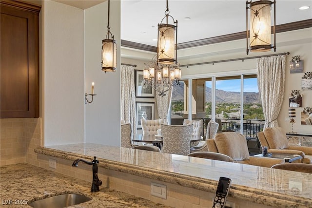 kitchen with hanging light fixtures, a mountain view, sink, and light stone countertops