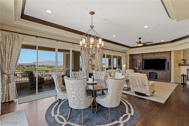 dining space with crown molding, dark hardwood / wood-style floors, a raised ceiling, and ceiling fan with notable chandelier