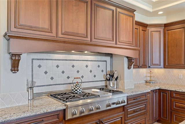 kitchen featuring stainless steel gas stovetop, tasteful backsplash, premium range hood, and light stone counters