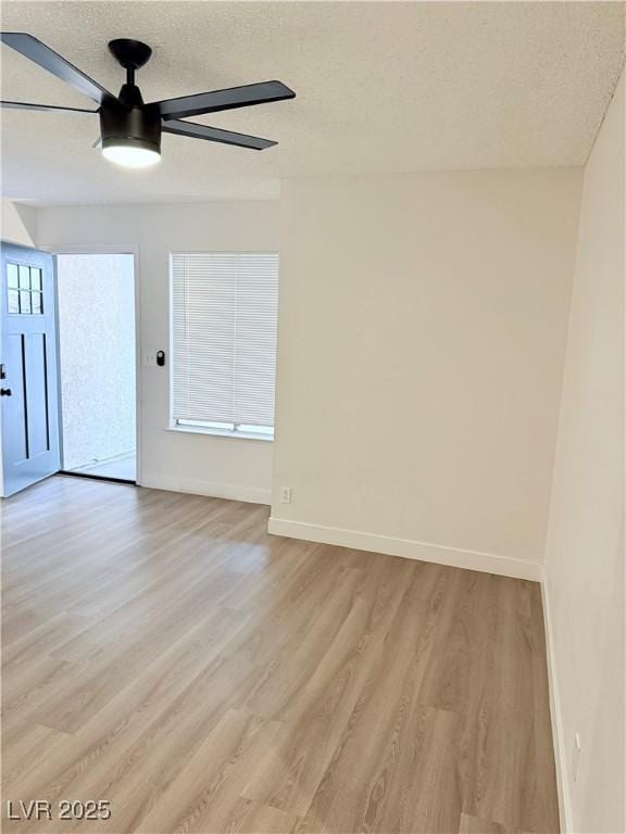 empty room featuring ceiling fan, light hardwood / wood-style floors, and a textured ceiling