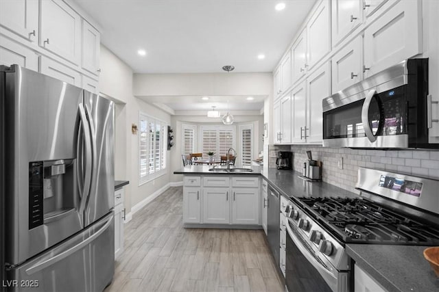 kitchen featuring appliances with stainless steel finishes, tasteful backsplash, sink, white cabinets, and kitchen peninsula