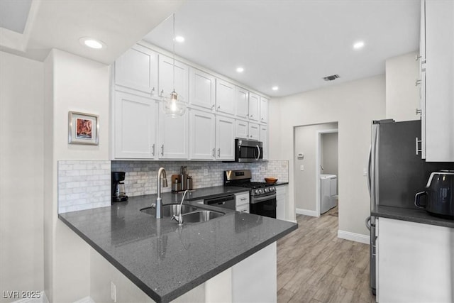 kitchen featuring washing machine and clothes dryer, sink, appliances with stainless steel finishes, kitchen peninsula, and white cabinets