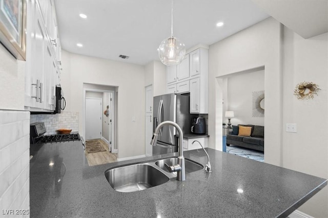 kitchen featuring sink, appliances with stainless steel finishes, white cabinetry, hanging light fixtures, and tasteful backsplash