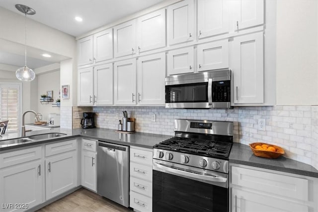 kitchen featuring pendant lighting, white cabinetry, sink, decorative backsplash, and stainless steel appliances