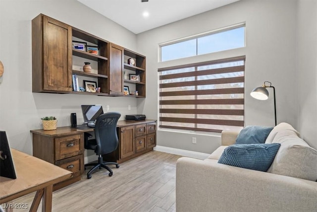 home office with built in desk and light hardwood / wood-style flooring