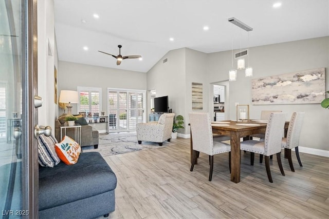 dining space with ceiling fan, high vaulted ceiling, and light hardwood / wood-style flooring