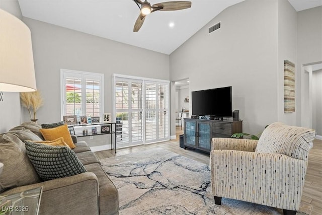 living room with light hardwood / wood-style flooring, high vaulted ceiling, and ceiling fan