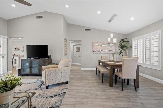 dining space with high vaulted ceiling and light wood-type flooring