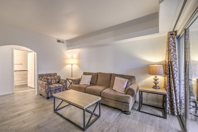 living area featuring visible vents, arched walkways, and wood finished floors