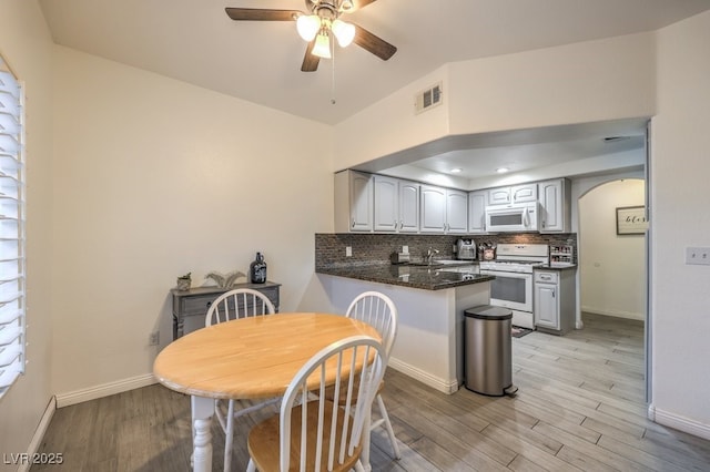 kitchen featuring tasteful backsplash, visible vents, light wood-type flooring, white appliances, and a peninsula