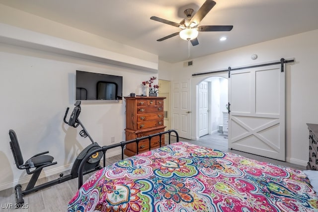 bedroom featuring baseboards, a barn door, visible vents, and wood finished floors