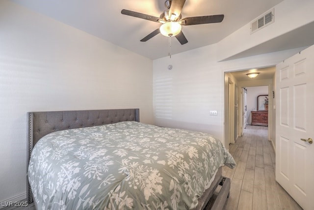 bedroom with light wood-style floors, visible vents, and a ceiling fan