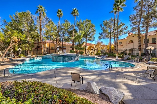 community pool with a patio area and fence