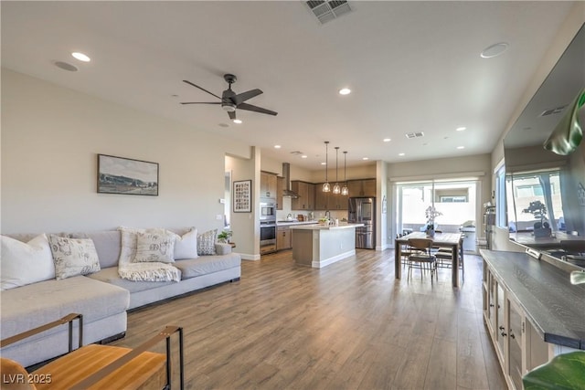 living room with sink, ceiling fan, and light wood-type flooring