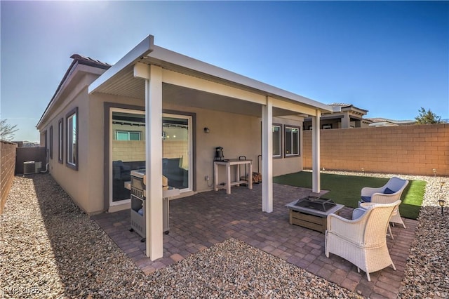 rear view of property featuring a patio, cooling unit, and a fire pit