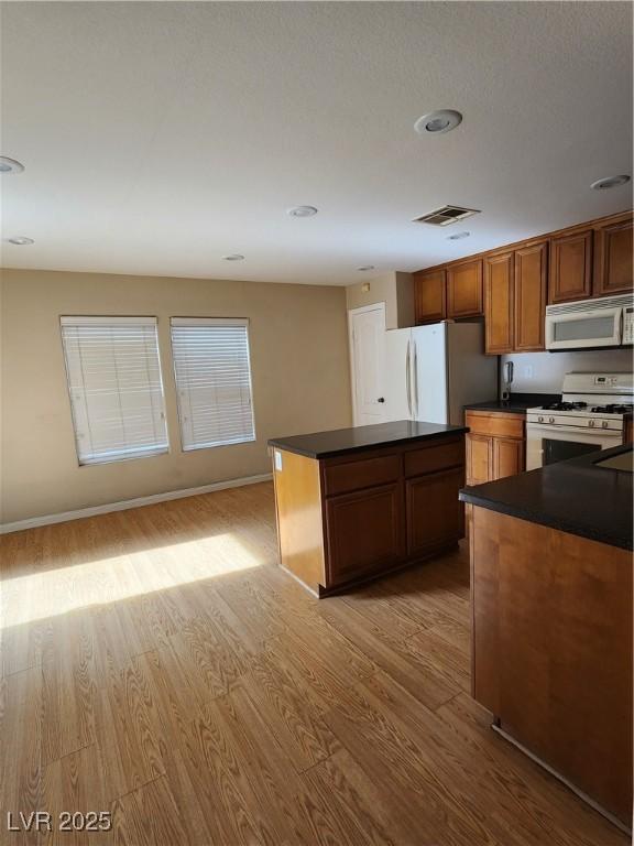 kitchen with white appliances, a center island, and light wood-type flooring