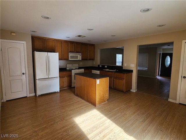 kitchen featuring white appliances, wood-type flooring, sink, and a kitchen island