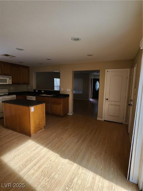 kitchen featuring a kitchen island, white appliances, and light hardwood / wood-style floors