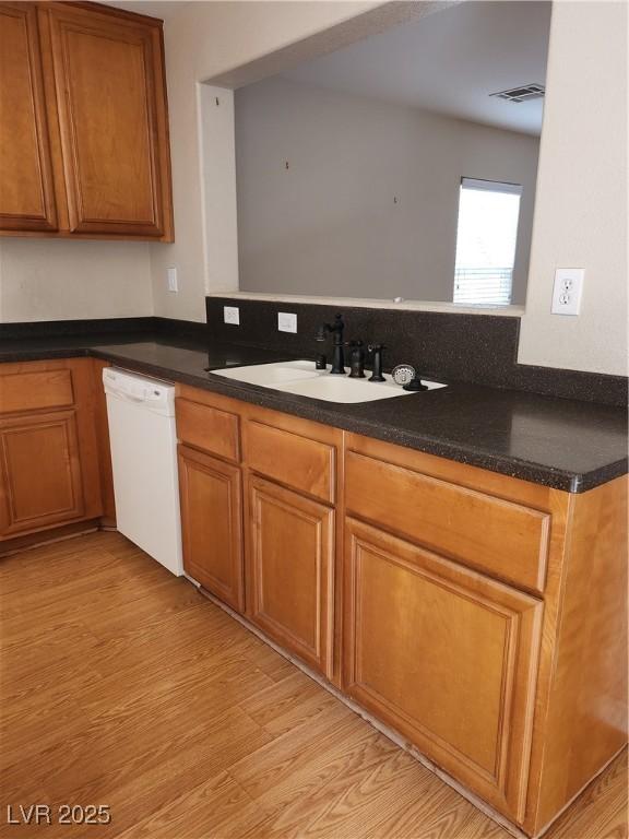 kitchen with kitchen peninsula, dishwasher, sink, and light hardwood / wood-style flooring