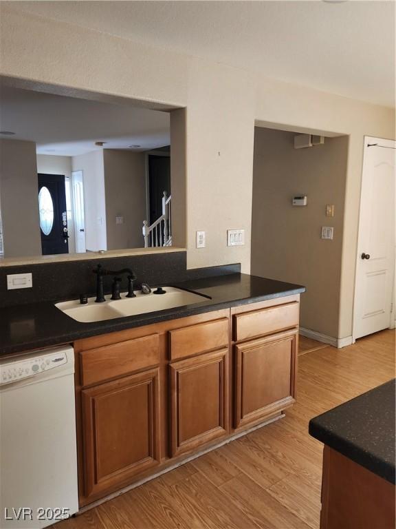 kitchen with sink, kitchen peninsula, white dishwasher, and light wood-type flooring