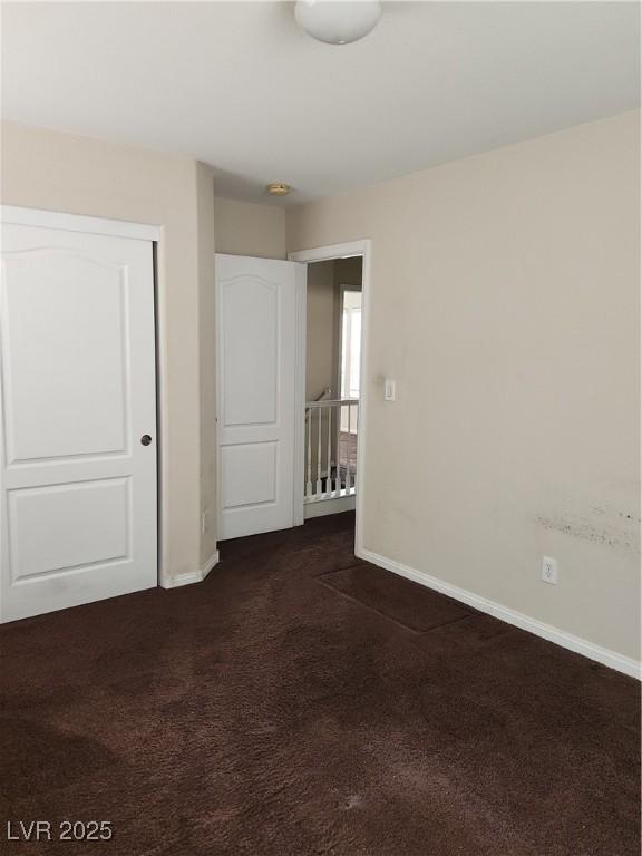 unfurnished bedroom with dark carpet and a closet