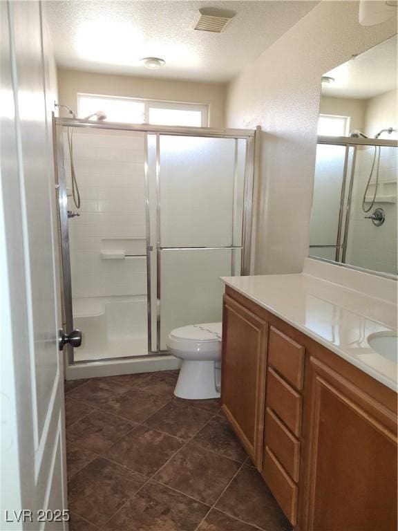 bathroom with vanity, toilet, a shower with door, and a textured ceiling