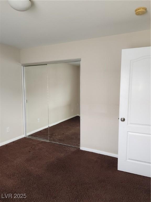 unfurnished bedroom featuring a closet and dark colored carpet