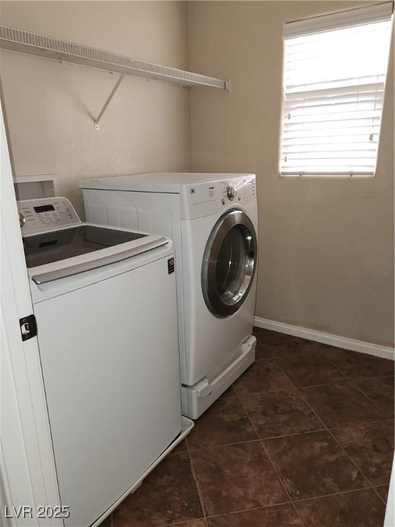 clothes washing area featuring dark tile patterned flooring and washer and dryer