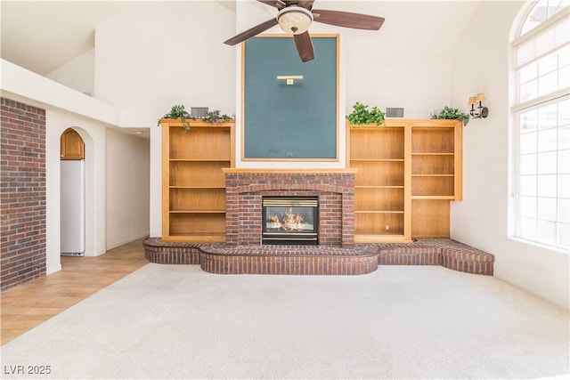 living room with ceiling fan, a fireplace, high vaulted ceiling, and hardwood / wood-style floors