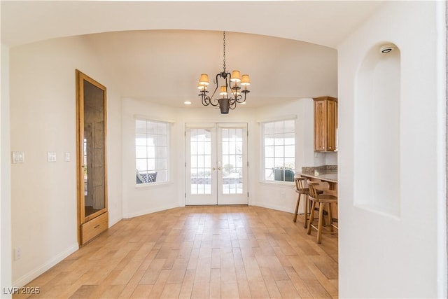 doorway with an inviting chandelier, french doors, and light wood-type flooring