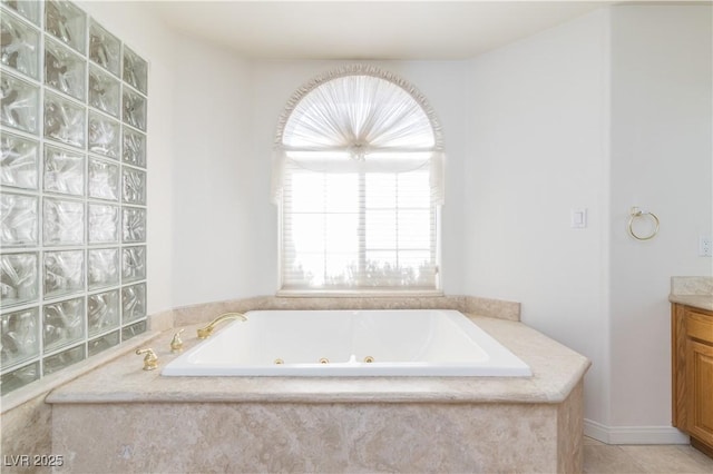 bathroom featuring tile patterned flooring, vanity, and tiled bath