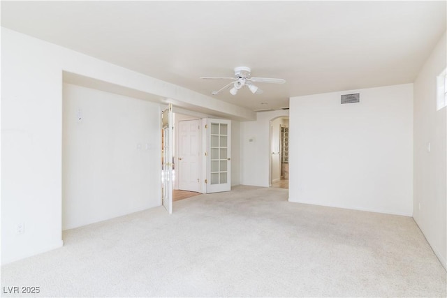 carpeted spare room featuring french doors and ceiling fan