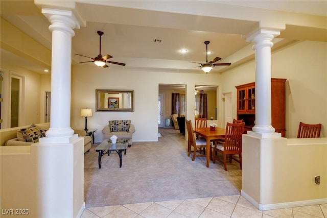 dining space with ceiling fan, a raised ceiling, light carpet, and ornate columns