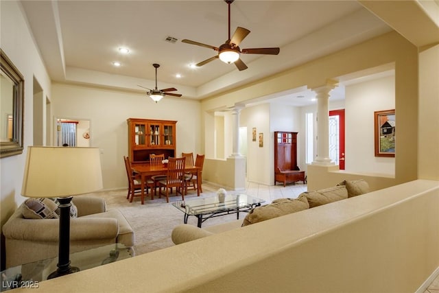 carpeted living room featuring ceiling fan, a tray ceiling, and decorative columns