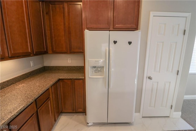 kitchen with dark stone countertops and white fridge with ice dispenser