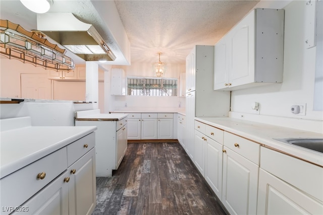 kitchen featuring sink, hanging light fixtures, dark hardwood / wood-style floors, a textured ceiling, and white cabinets