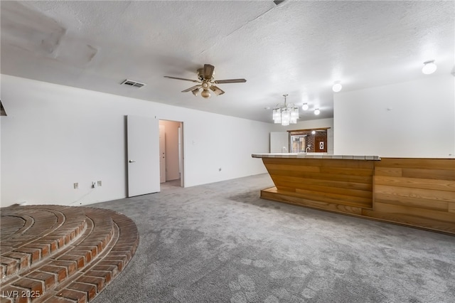 interior space with ceiling fan with notable chandelier, light colored carpet, and a textured ceiling