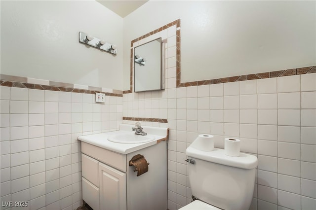 bathroom with vanity, tile walls, and toilet