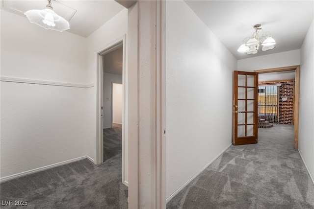 hall featuring a chandelier and dark carpet