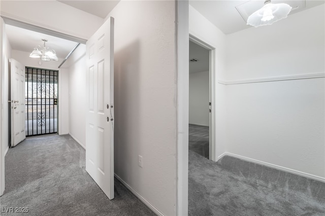 corridor with a notable chandelier and dark carpet