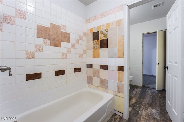 bathroom featuring toilet, a bath, and hardwood / wood-style floors