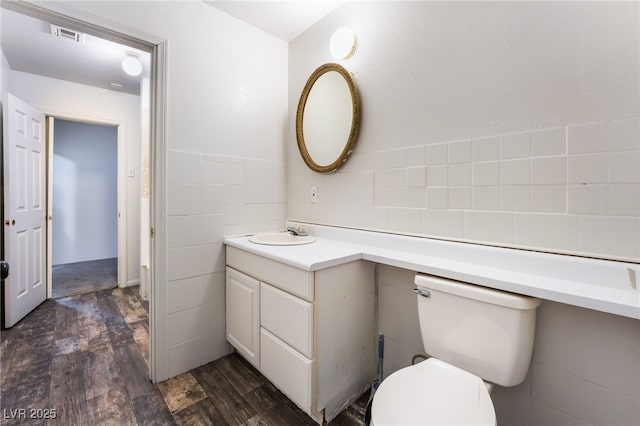 bathroom featuring vanity, hardwood / wood-style floors, tile walls, and toilet