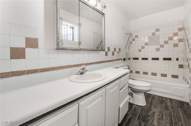 full bathroom featuring hardwood / wood-style flooring, vanity, tasteful backsplash, tiled shower / bath, and toilet