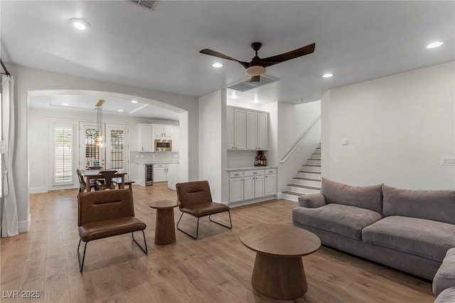 living room with ceiling fan, wine cooler, and light wood-type flooring