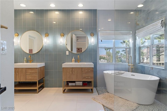 bathroom with tile patterned flooring, vanity, a bathtub, and tile walls