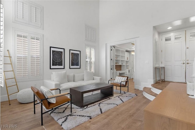 living room with a towering ceiling and light wood-type flooring