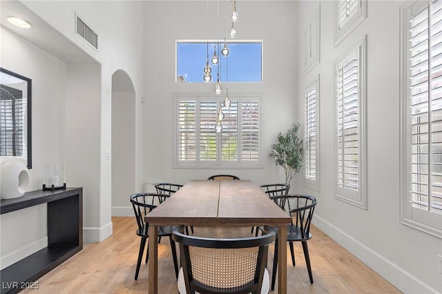 dining room with light hardwood / wood-style floors and a high ceiling