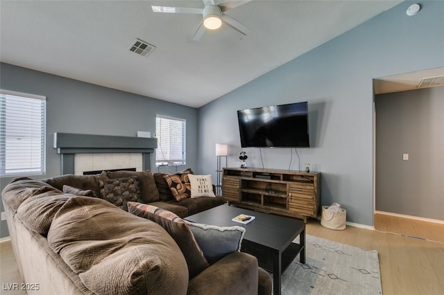 living room featuring lofted ceiling, a fireplace, light hardwood / wood-style flooring, and ceiling fan