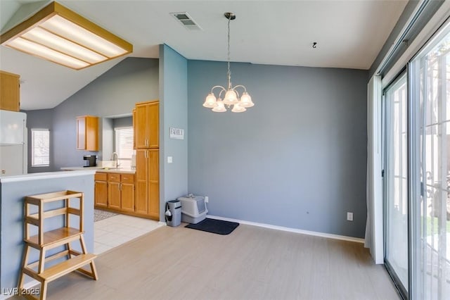 kitchen with sink, a chandelier, vaulted ceiling, hanging light fixtures, and light hardwood / wood-style floors